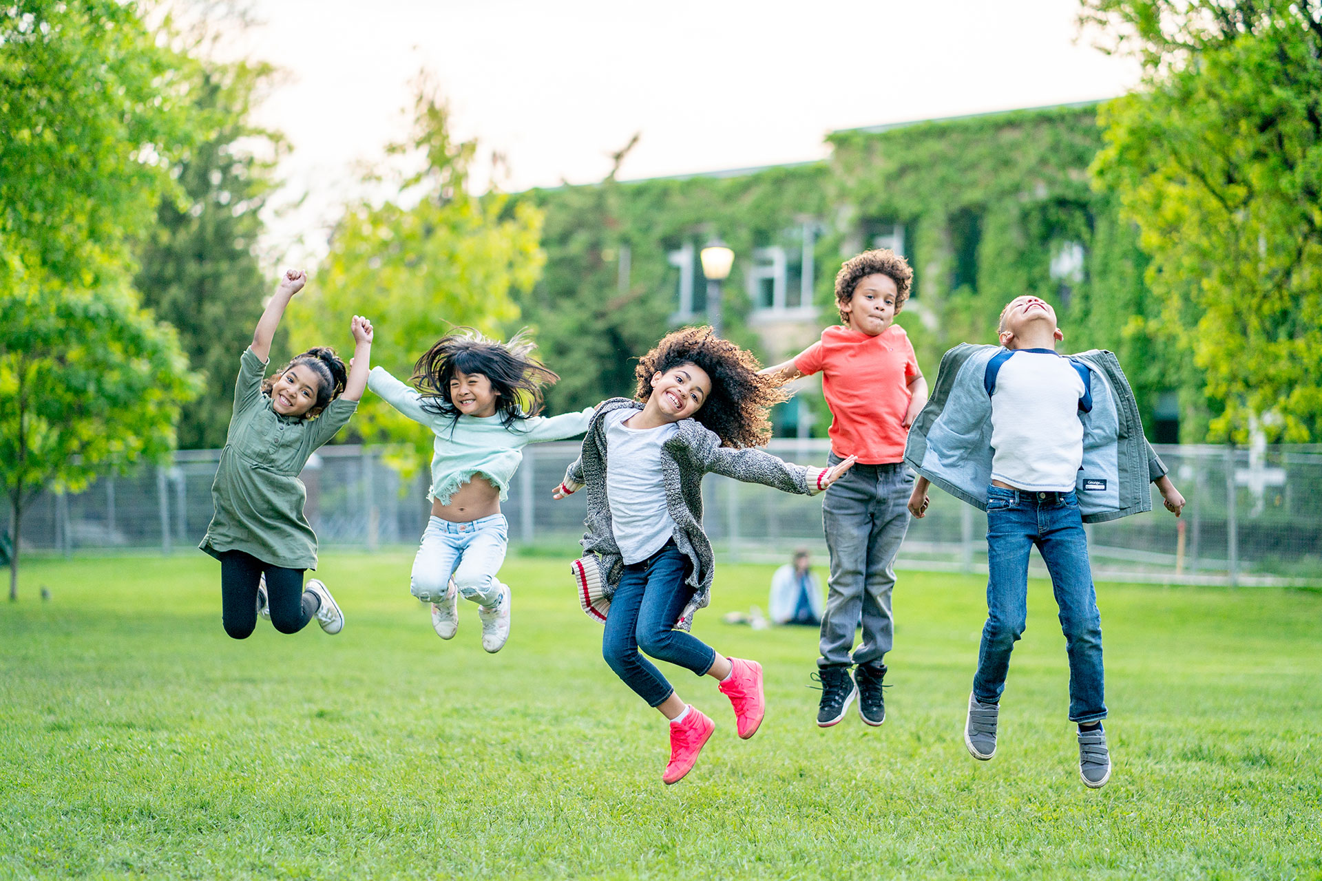 group of children jumping in a grassy field
