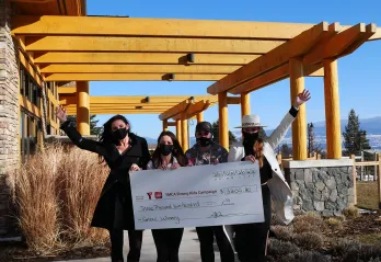 4 women outside holding a big cheque