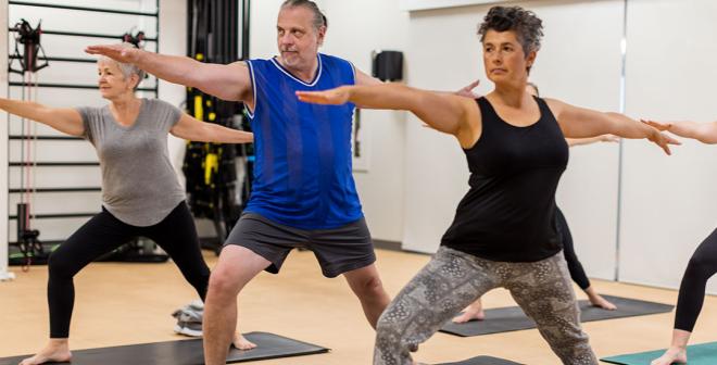 group of older adults practicing the warrior 2 pose in a yoga class at the Kelowna Downtown Y