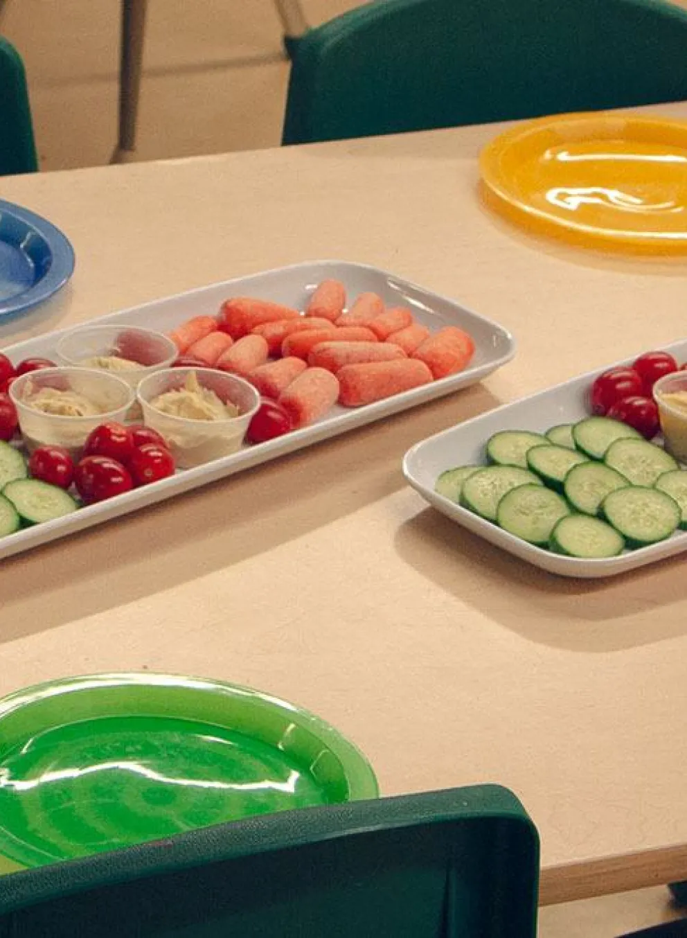 trays of vegetables and hummus surrounded by colourful plates and chairs