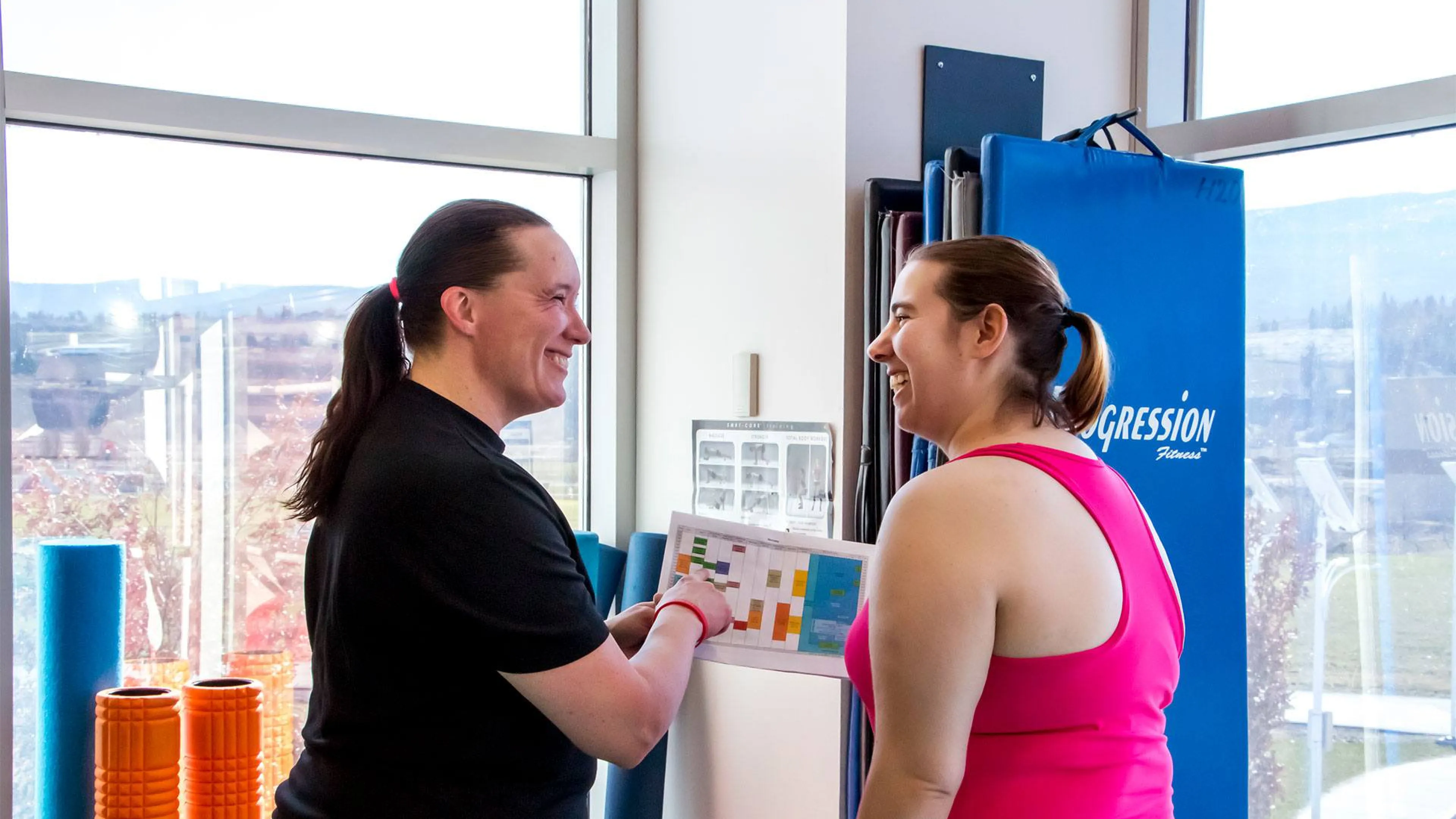 Two women consulting a printed schedule at H2O