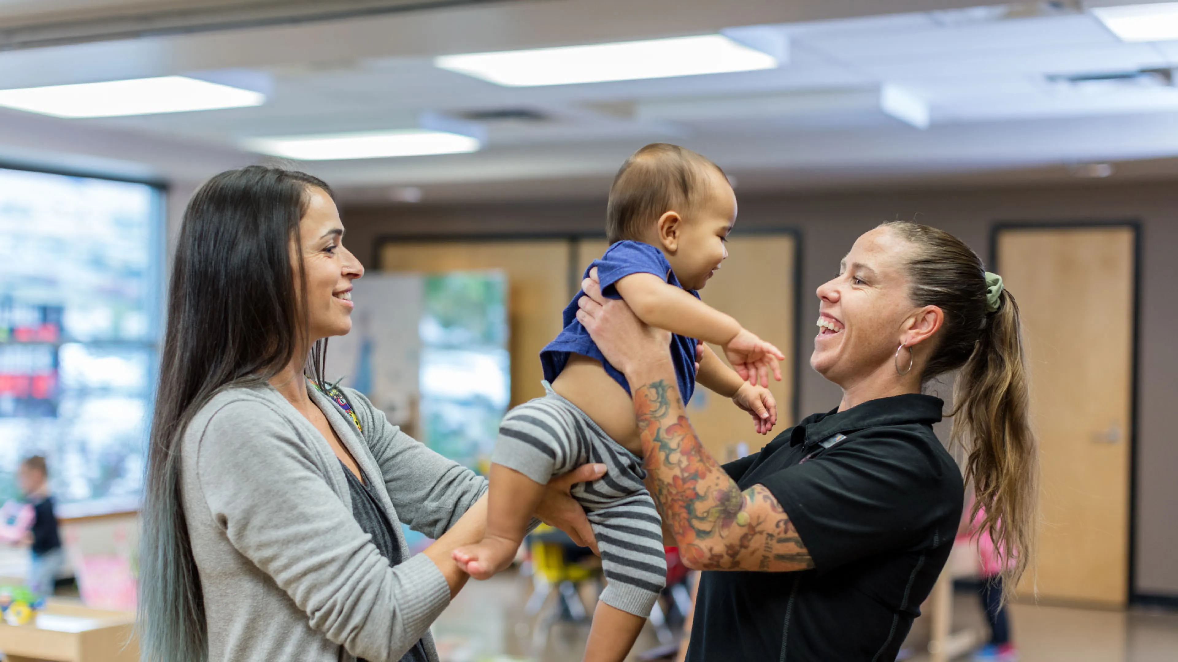 mom passes baby to YMCA child minding staff person