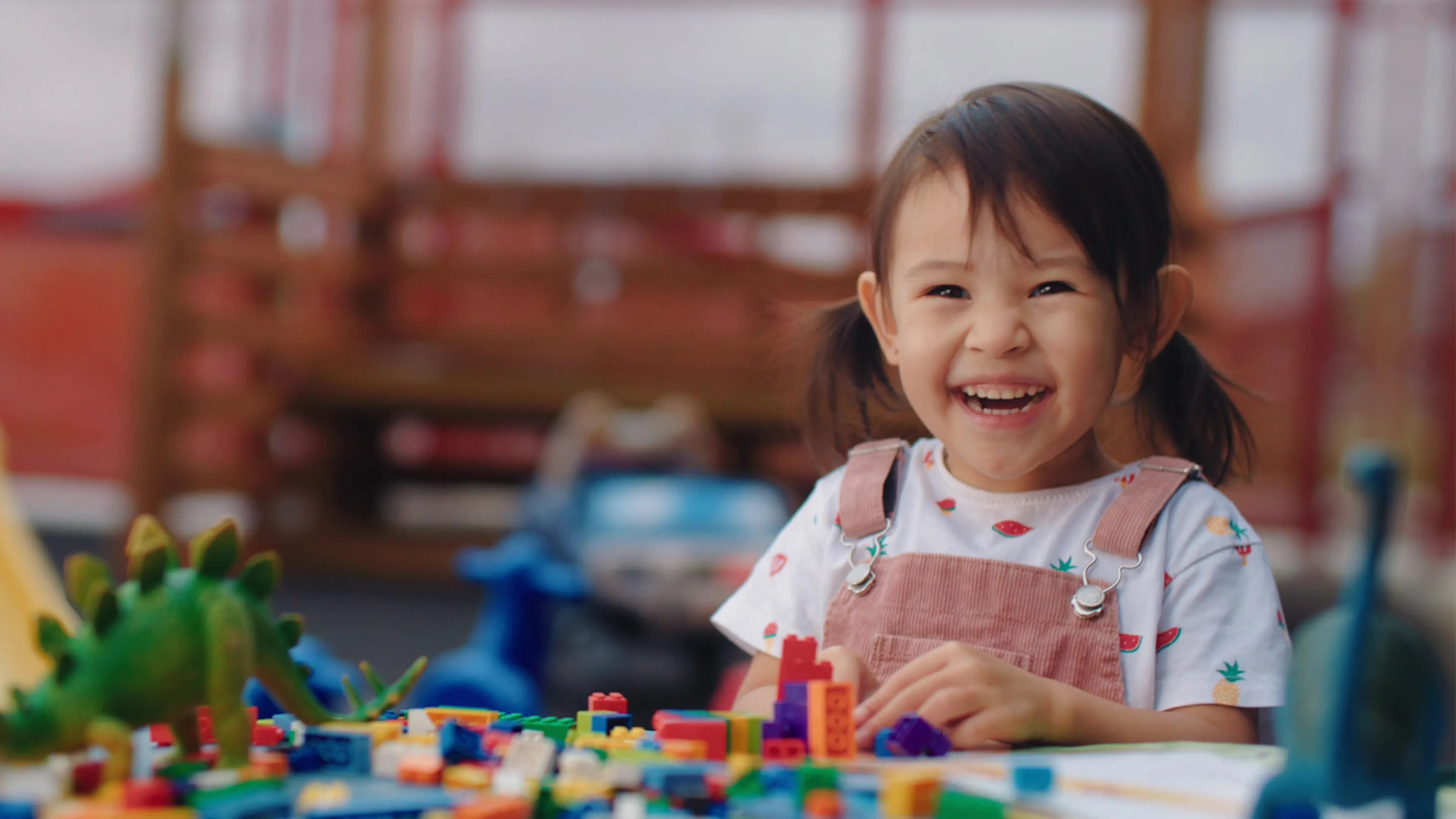 smiling child at table with LEGO blocks