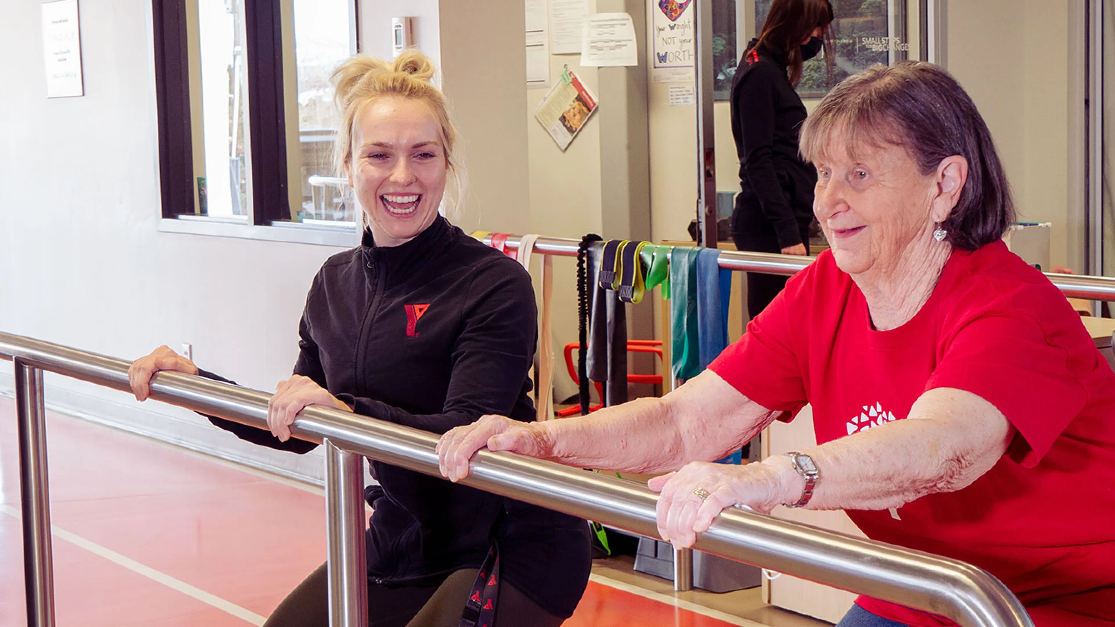 Healthy Hearts participant and coach stretch using railing