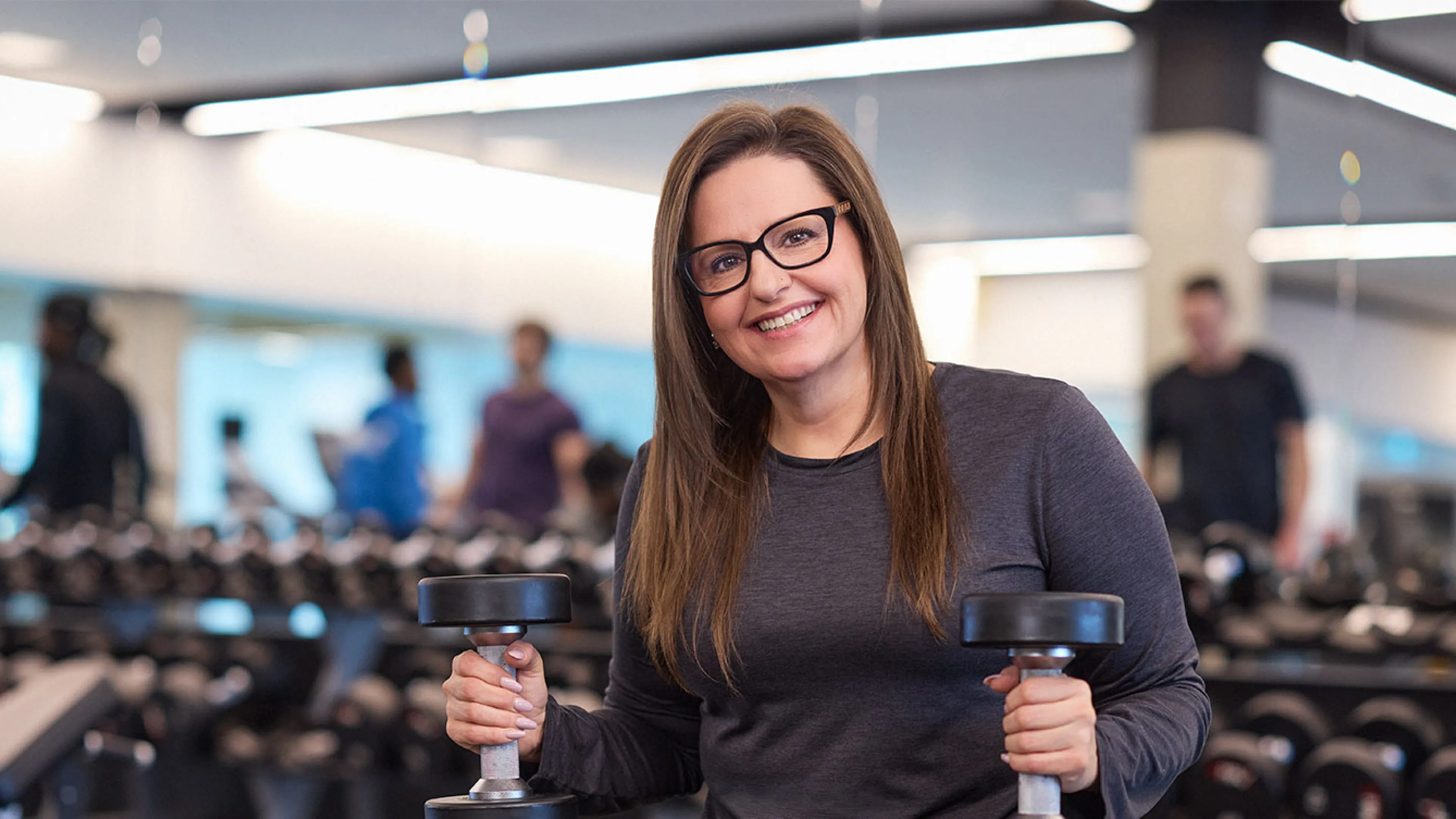 happy and confident woman holding weights