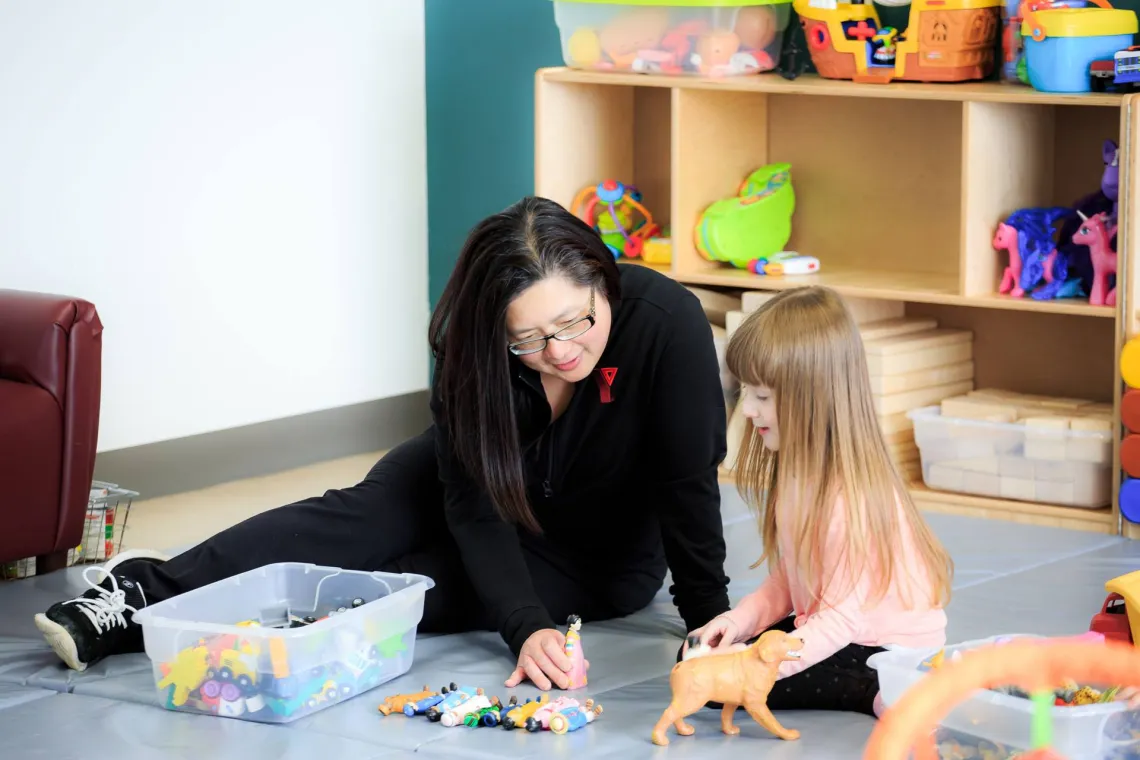 YMCA early childhood educator and child play imaginative game with toys