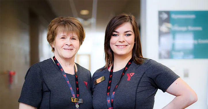 two smiling YMCA staff wearing branded shirts, nametags and lanyards