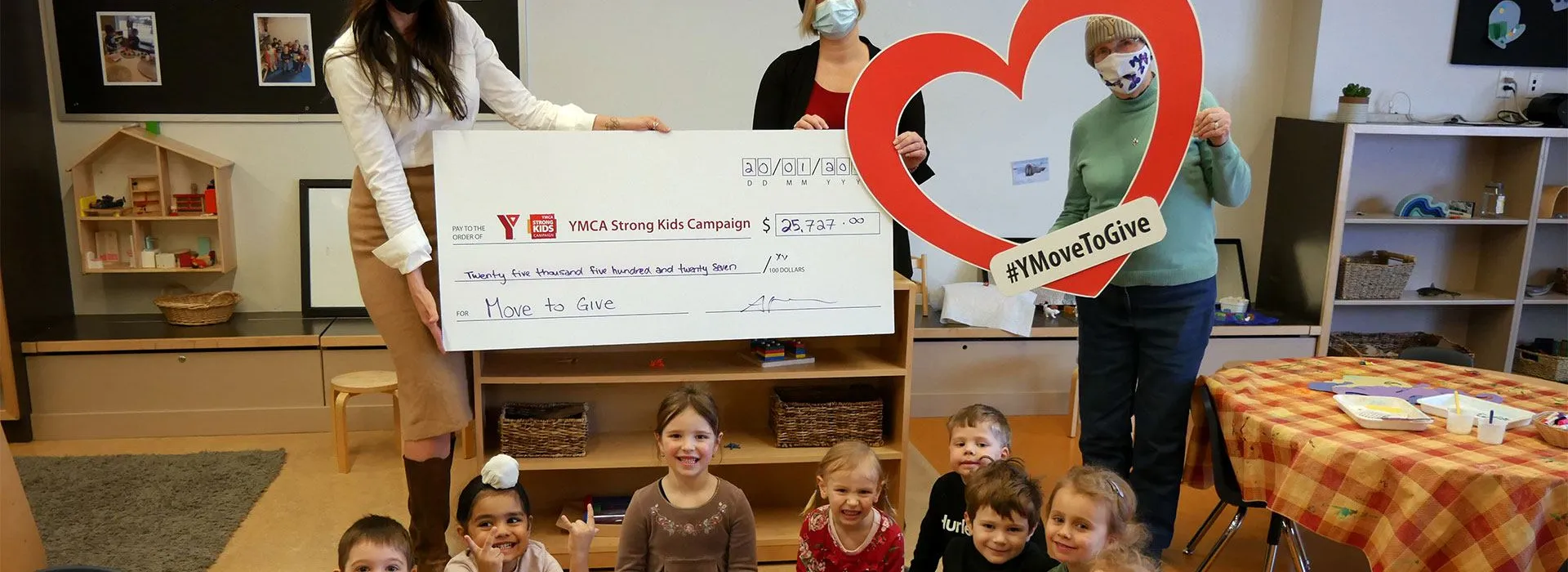 ladies holding cheque with kids in front