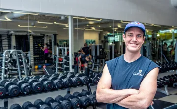 Austin smiling in front of the free weights
