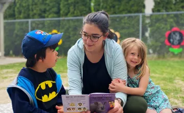 2 children and a woman reading a book
