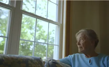 woamn in a white sweater looking out a window