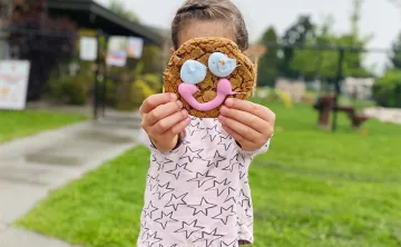 Kid holding up cookie on face