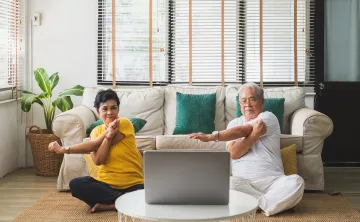 2 seniors stretching at home with a computer