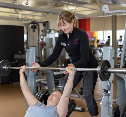 YMCA trainer spotting someone using the bench press