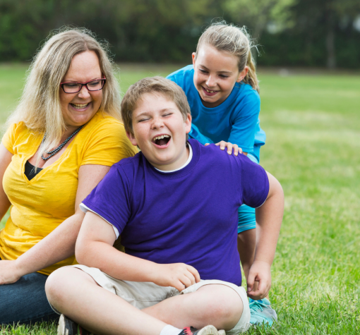 Two Children and a parent sitting in a park.
