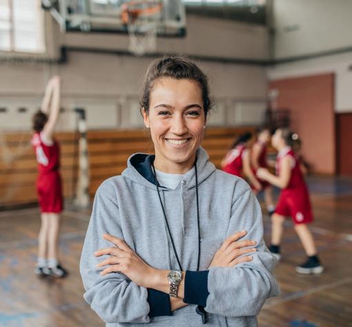 basketball coach in gymnasium with team playing behind