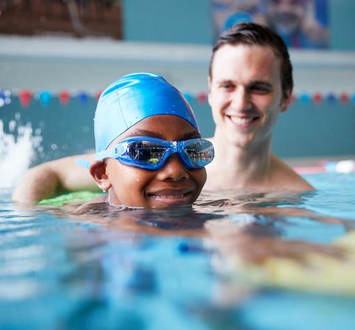 young man helps child swim