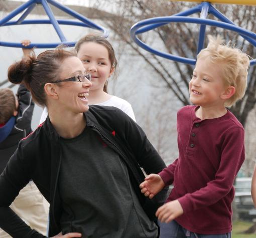 Staff and children laughing in playground at Queen's Park YMCA Child Care