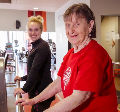 Healthy Hearts participant and coach stretch using railing
